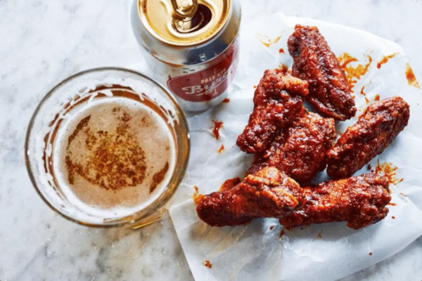 Food videography showing a plate of chicken wings along side a glass of beer and the can