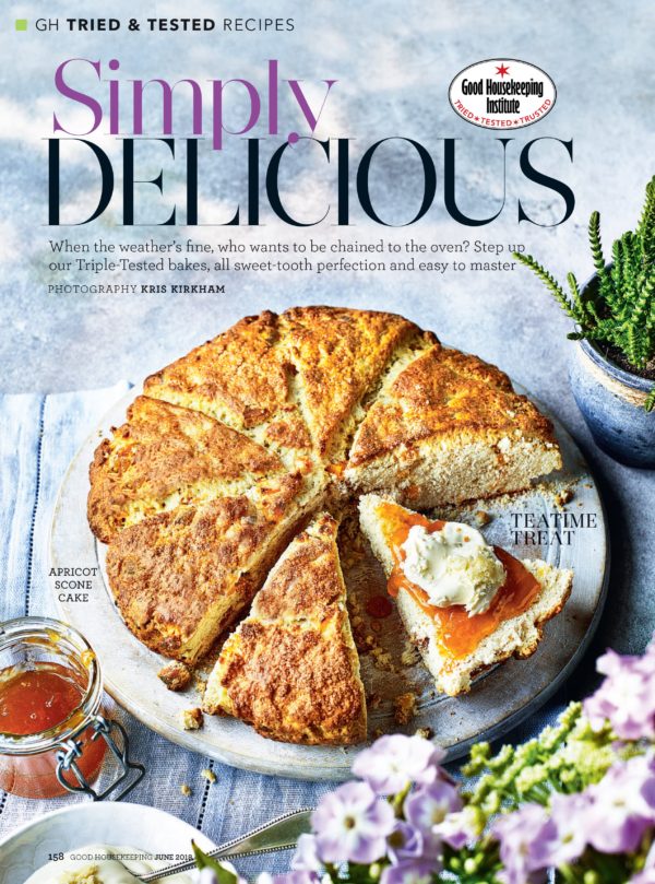 Creative food photography showing a large sliced apricot scone cake, with a piece about to be eaten decorated with jam and cream