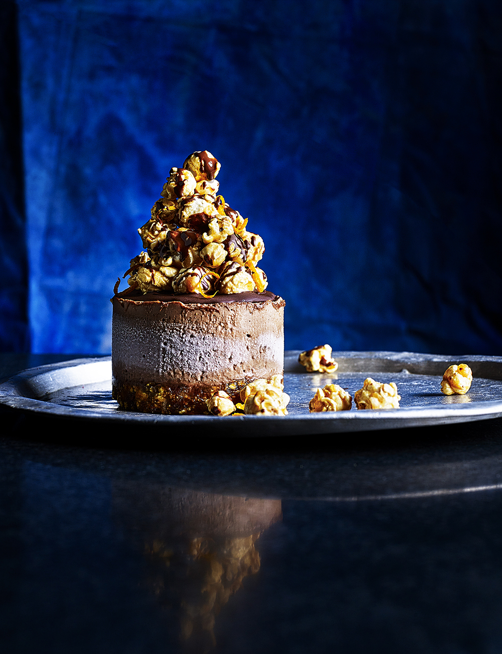 Food photography showing a cheesecake topped with a pile of popcorn