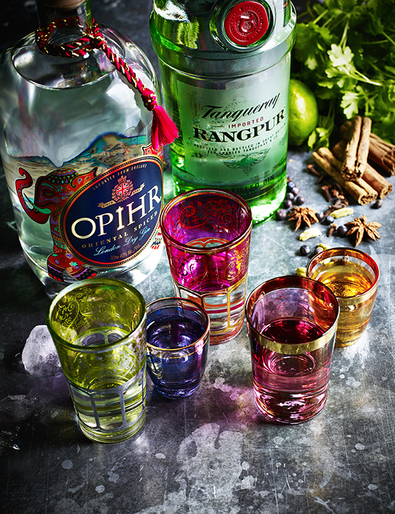 Food photography for advertising showing an array of colourful gins from Asia, captured alongside colourful shot glasses ready to pour