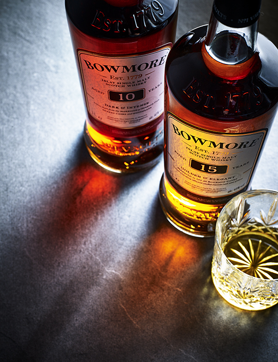 Food photography for advertising showing two bottles of Bowmore single malt whiskey, casting a shadow onto the surface with a glas spoured and ready to drink
