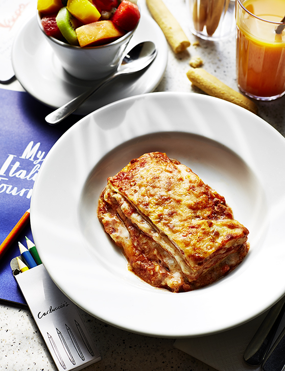 Food photography for advertising showing lasagne, surrounded by cutlery and side dishes