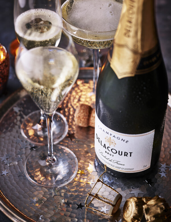 Food photography for advertising created for M&S magazine showing a bottle of Delacourt sparkling wine with two glasses poured.