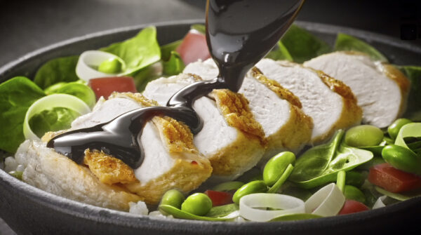 Restuarant food videography to Itsu showing sauce being poured over chicken and vegetable dish.